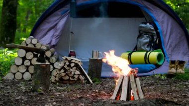 Yanan bir ateş ve günlükleri bir turist çadır arka planda yanmak.