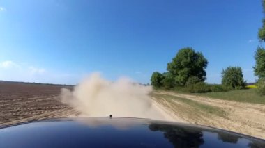 Otomobil araba lastikleri sürüş kırsal çakıl yolda yükselen toz. POV geri hareket görünümü.