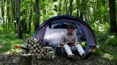 Backpacker açık havada bir tablet kullanır. Bahar yeşil orman.