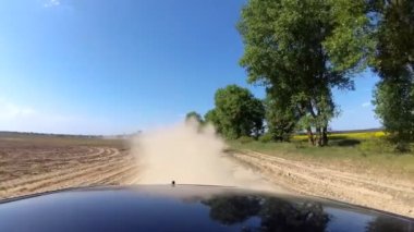 Otomobil araba lastikleri sürüş kırsal çakıl yolda yükselen toz. POV geri hareket görünümü.