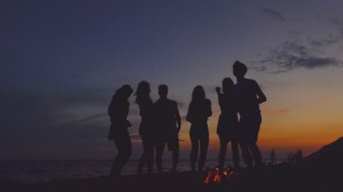 Bir grup insan şenlik yakınındaki plajda dans. Ağır çekim.