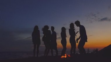 Bir grup insan şenlik yakınındaki plajda dans. Ağır çekim.