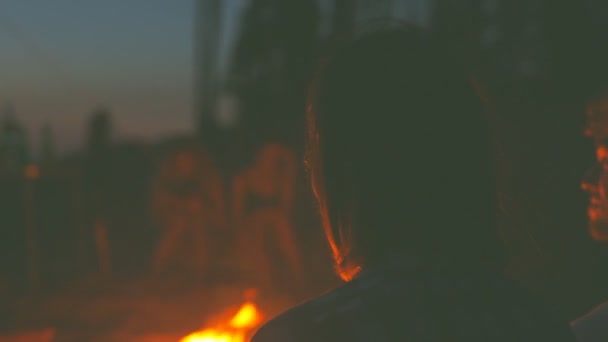 Groupe d'amis se détendre autour du feu de joie sur la plage et s'amuser .