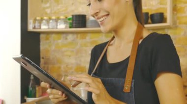 Çekici bir kız (bir kahve evin sahibi) bir tablet üzerinde çalışır. Ağır çekim.