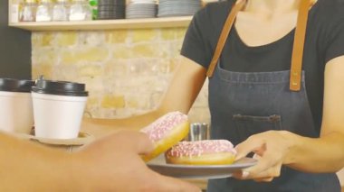 Fincan kahve ve donats müşteriye vererek garson gülümseyerek.