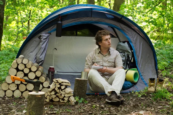 Backpacker bir defterde açık havada notlar alır. Doğada kamp. 