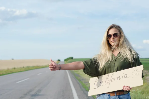 Серйозна Блондинка Тримає Знак Під Час Автостопінгу Дорозі Влітку — стокове фото