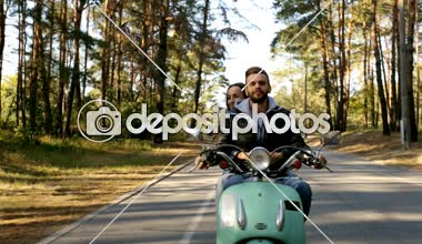 Mutlu çift ormandaki bir scooter sürme. Güneşli güzel gün.