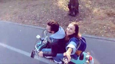 Mutlu çift ormandaki bir scooter sürme. Güneşli güzel bir gün. Selfie-stick kamera görüntüsü. Ağır çekim.