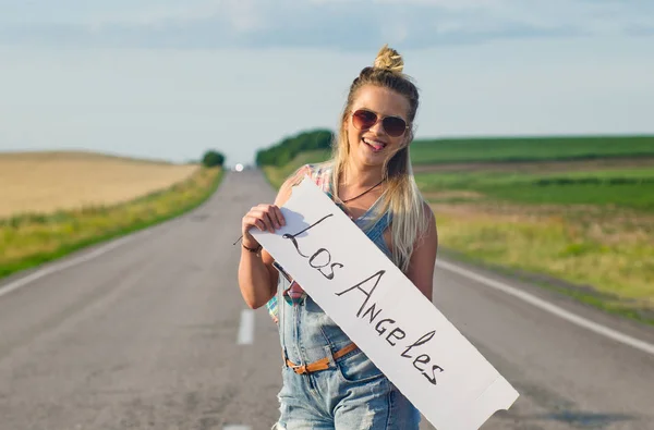 夏に道でヒッチハイクしながらサインを保持している金髪 — ストック写真
