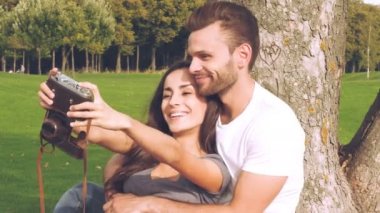 Mutlu çift yeşil çimenlerin üzerinde kendilerini eski bir kamera ile fotoğraf çekimi.