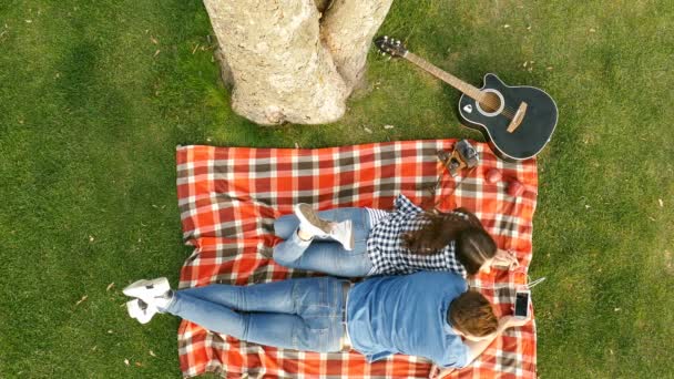 Glückliches Paar Das Unter Einem Baum Liegt Und Musik Hört — Stockvideo
