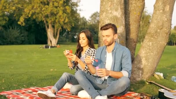Lyckligt Par Blåser Bubblor Sittande Ett Stort Träd Campus — Stockvideo