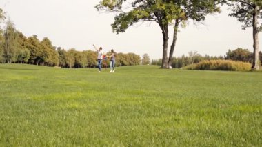 Mutlu çiftimiz parkta yeşil çim üzerinde bir uçurtma uçan.