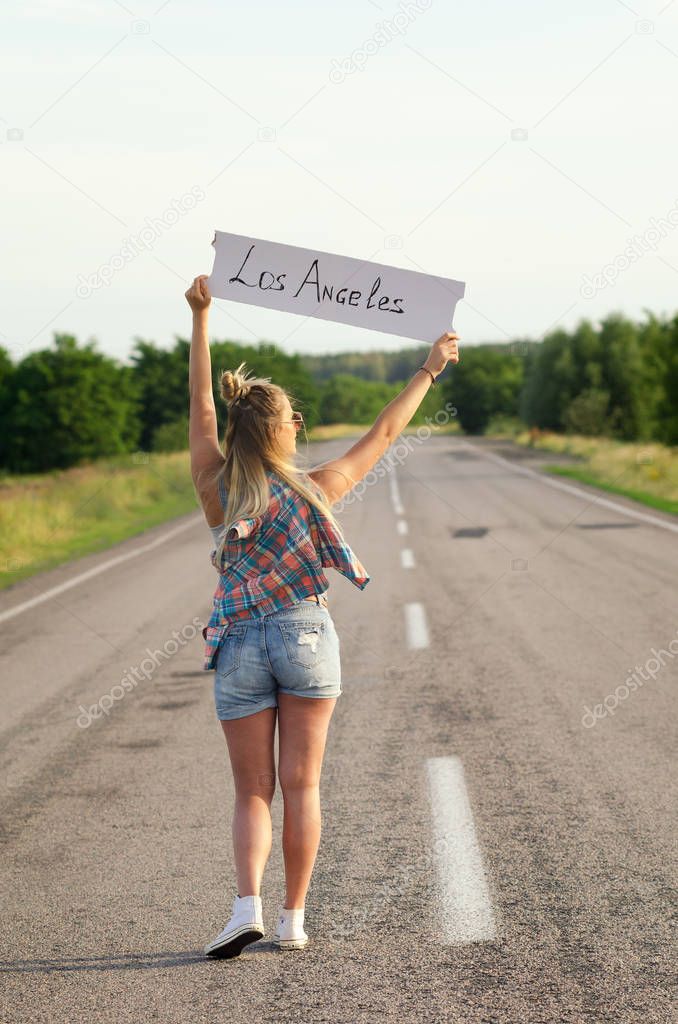 Beautiful Girl Hitchhiking On The Road Traveling.