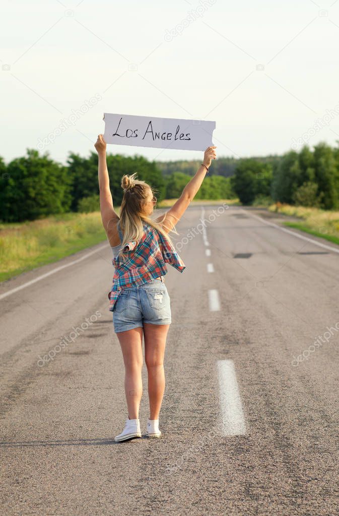 Beautiful Girl Hitchhiking On The Road Traveling.