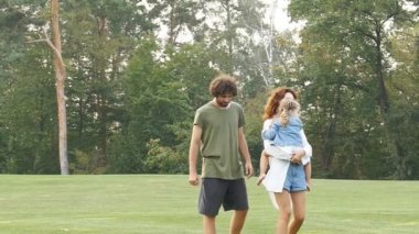 Mutlu bir aile parkta birlikte yürüyor. Yavaş çekim video