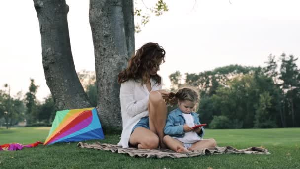 ママは公園の緑の芝生の上で小さな娘と遊ぶ — ストック動画