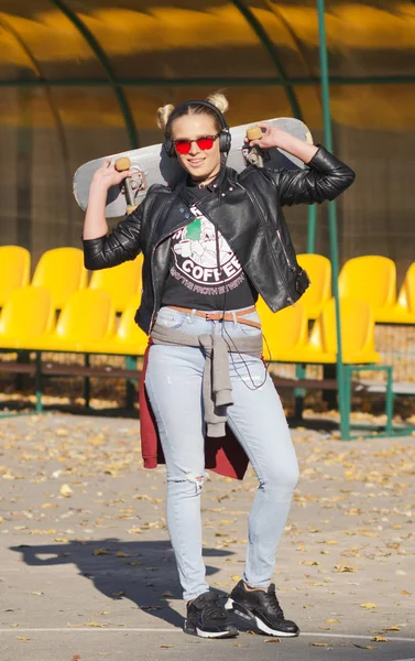 Hipster chica posando con un monopatín . —  Fotos de Stock