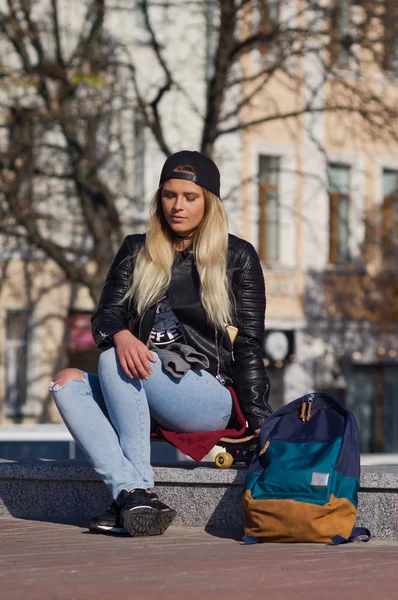 Mädchen lächelt glücklich, sitzt auf Skateboard. — Stockfoto