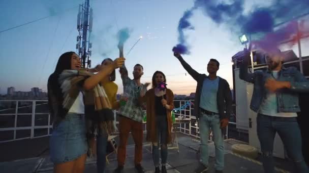 一群朋友挥舞着烟雾弹和火花 晚上在屋顶上享受派对 — 图库视频影像