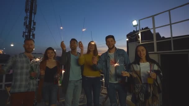 一群朋友挥舞着火花 晚上在屋顶上享受派对 — 图库视频影像