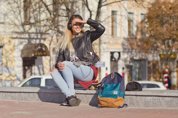 Bayan kız mutlu gülümsüyor, kaykay oturur.