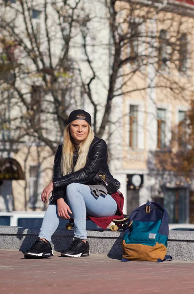 Mädchen lächelt glücklich, sitzt auf Skateboard. — Stockfoto