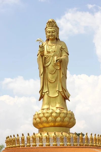 Açık bir gökyüzü arka plan üzerinde Altın Guanyin heykeli.