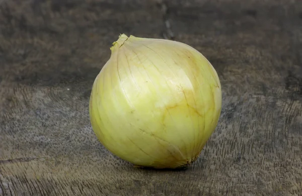 Close up one onions on wooden floor . — стоковое фото