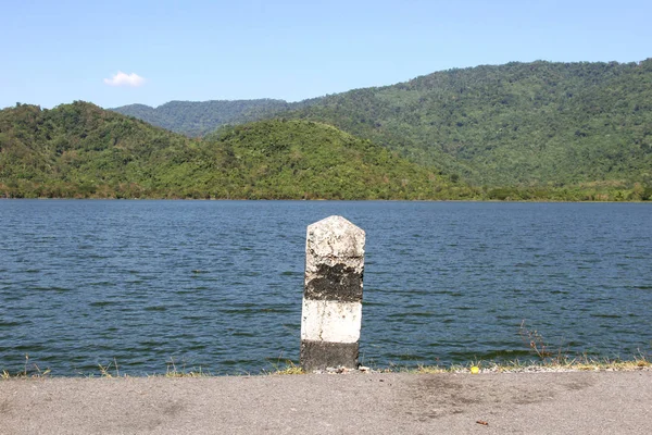 Hitos viejos, blancos y negros con hierba verde en la carretera —  Fotos de Stock