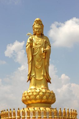 Açık bir gökyüzü arka plan üzerinde Altın Guanyin heykeli.