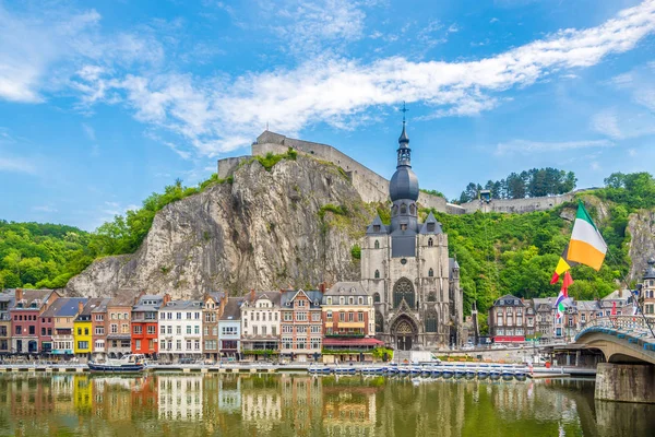 View at the embankment of Meuse river with houses and church of Our Lady Assumption in Dinant, Belgium