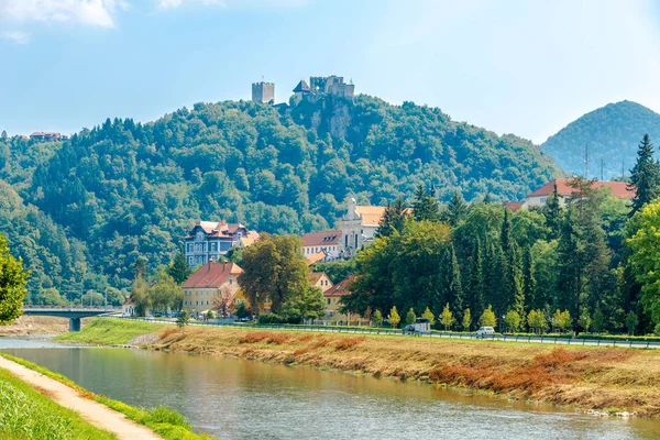 Widok na rzekę Savinja ze starym zamkiem na wzgórzu w tle w Celje-Słowenia — Zdjęcie stockowe