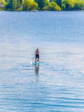 Göl sahile doğru kürek çekmeye bir paddleboard adam