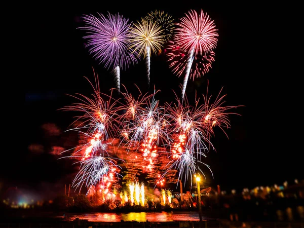 Fogos de artifício coloridos com múltiplas explosões contra o céu escuro — Fotografia de Stock