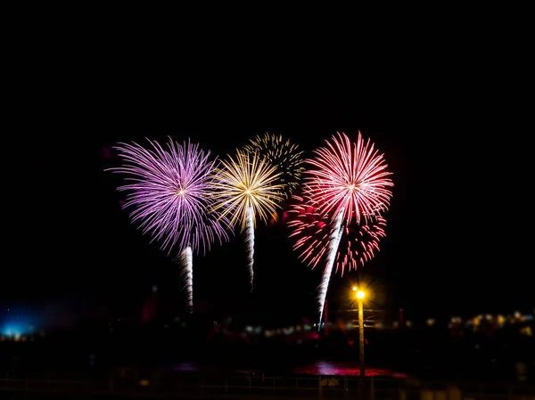 Fogos de artifício coloridos com múltiplas explosões contra o céu escuro — Fotografia de Stock