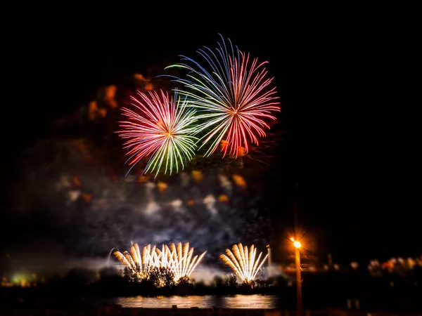 Fogos de artifício coloridos com múltiplas explosões contra o céu escuro — Fotografia de Stock