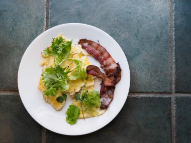 Granit counterto üzerinde yumurta ve domuz pastırması kahvaltı ile beyaz plaka