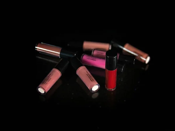 Variety of lipsticks and lip gloss over black background