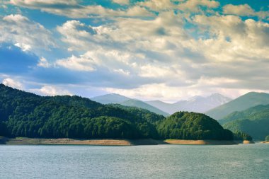 Bulutlu gökyüzünün altında yeşil dağlar