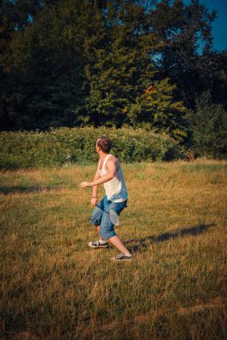 Genç adam gündüz vakti çayırda badminton oynuyor. 