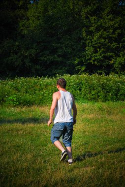 Genç adam gündüz vakti çayırda badminton oynuyor. 