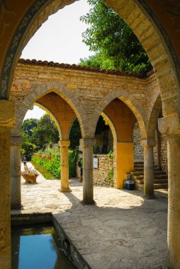 Eski bahçedeki yeşil bitkilerle sütunlar ve kemerler 