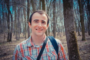 Gündüz vakti sonbahar parkında duran genç adamın portresi.