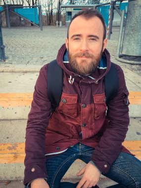 Sırt çantalı genç bir gezgin gündüz vakti sokakta oturuyor. 