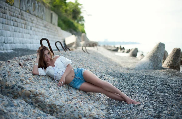 性感的女孩在装饰品 Bocho 躺在一个荒凉的石质海滨 — 图库照片