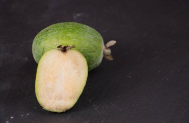 Olgun feijoa meyvesi karanlık kayrak gri bir arka plan üzerinde kesmek