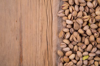 Eski bir ahşap masanın üzerindeki el işi parşömende kızarmış tuzlu şam fıstığı serpilmesi. Üst Manzara. Tasarım için arkaplan