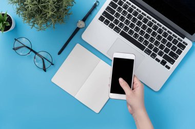Ev ofis masa moda aksesuarları ile düz yatıyordu, bir kadın tutarak smartphone ile en az iç kavramı kopya alanı, üstten görünüm, mockup
